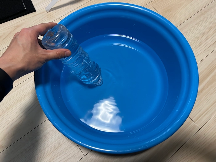 水素吸入器の水素ガス発生量を確かめるためにペットボトルを桶に入れる