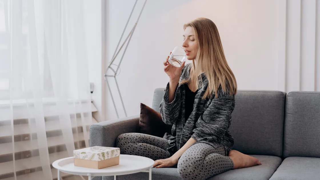 Woman drinking water on sofa