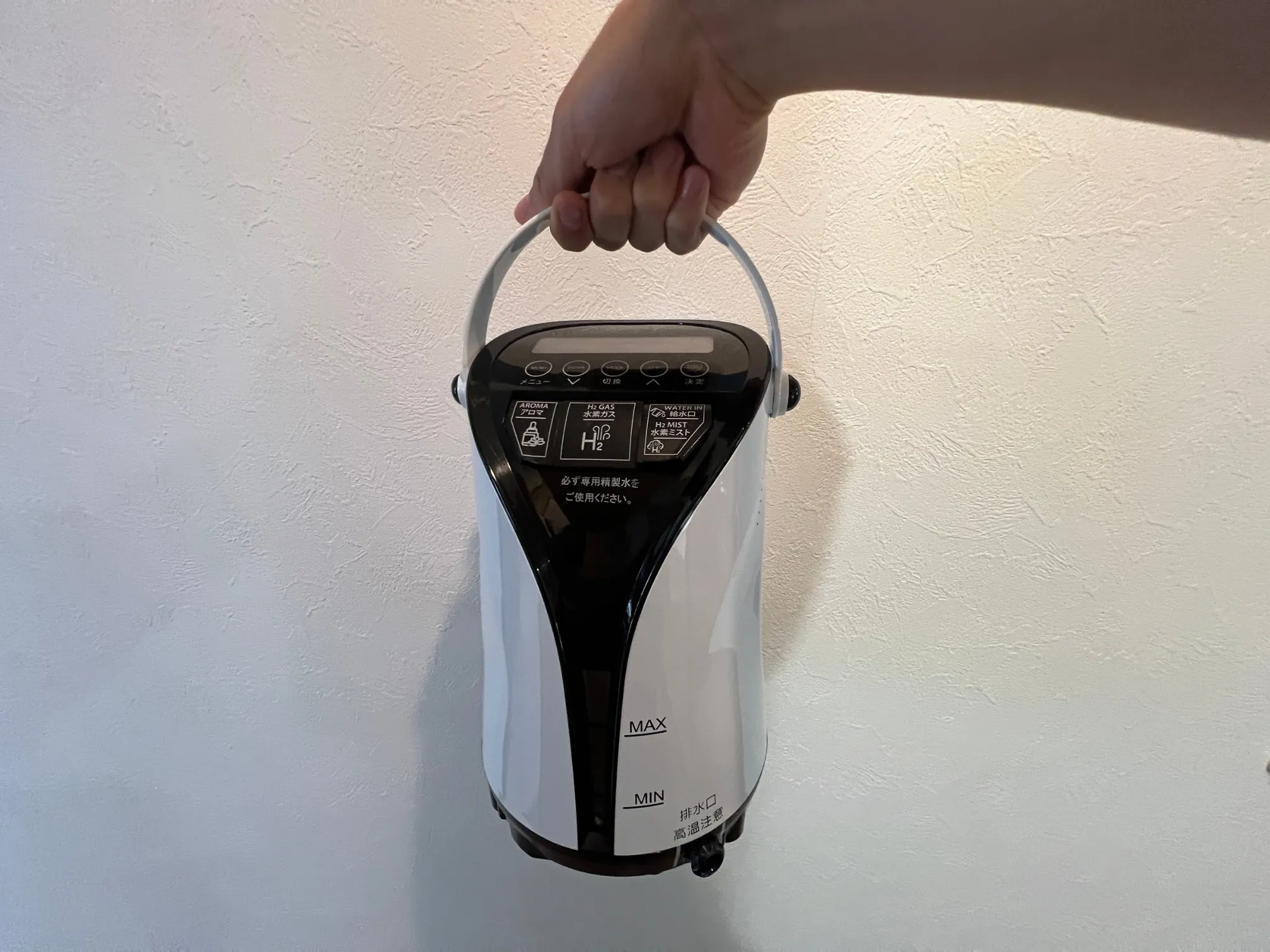 水素吸入器「リタエアー」の取手を持って持ち上げている様子